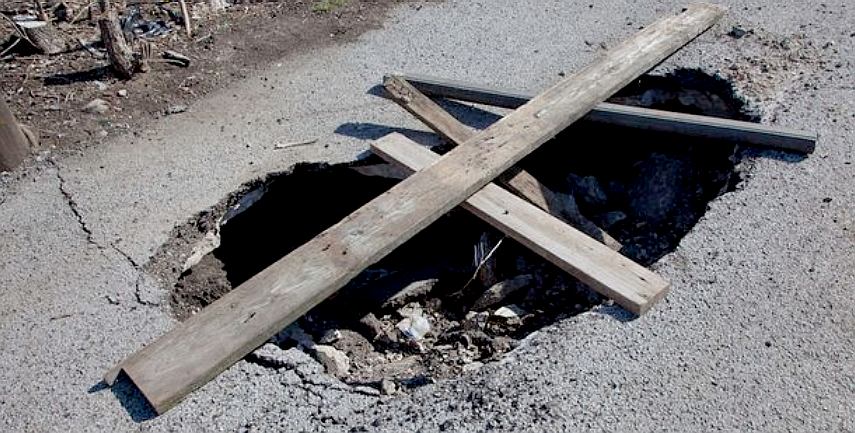 Planks of wood across a dangerous pothole